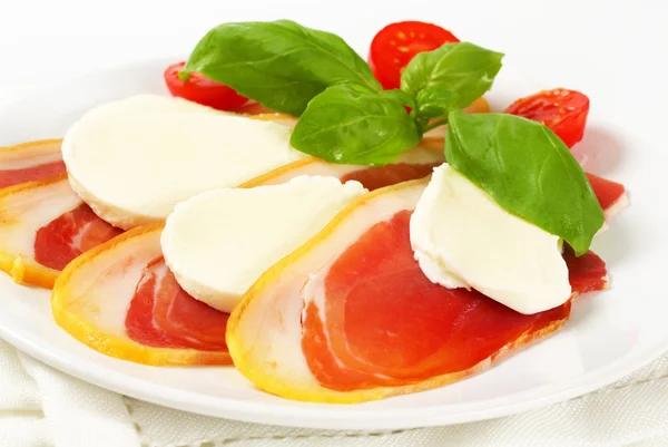 Plasterki szynki i mozzarella z pomidorami i bazylią — Zdjęcie stockowe
