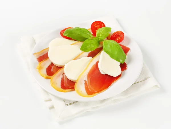 Plasterki szynki i mozzarella z pomidorami i bazylią — Zdjęcie stockowe