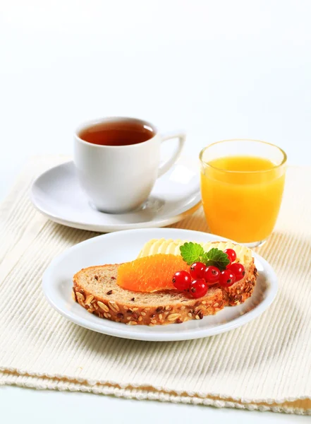 Brot mit Butter, Tee und Orangensaft — Stockfoto