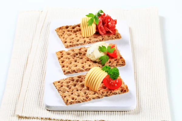 Whole grain crispbread with various toppings — Stock Photo, Image