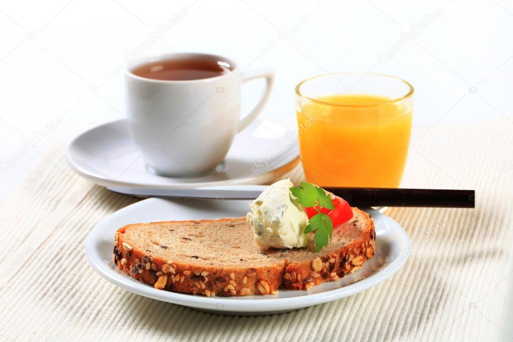 Bread with cheese spread, cup of tea and orange juice