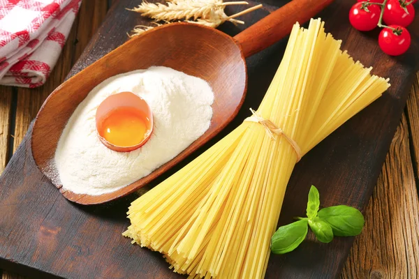 Dried spaghetti and scoop of flour with fresh egg — Stock Photo, Image