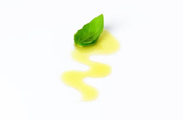 Olive oil drizzle and basil leaf — Stock Photo, Image