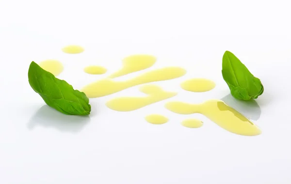 Olive oil drizzle and basil leaves — Stock Photo, Image