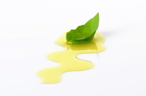 Olive oil drizzle and basil leaf — Stock Photo, Image