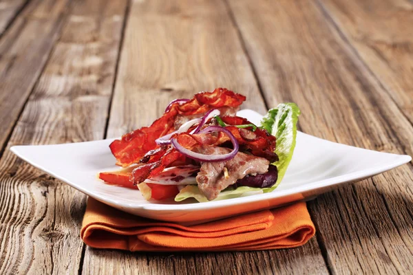 Meat skewer and crispy bacon strip — Stock Photo, Image