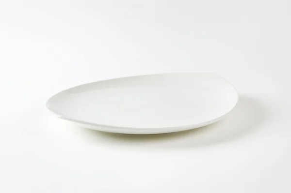 Flat oval white porcelain plate — Stock fotografie