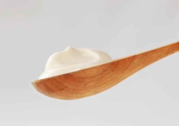 Crema blanca sobre una cuchara de madera — Foto de Stock