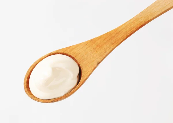 Crema blanca sobre una cuchara de madera — Foto de Stock