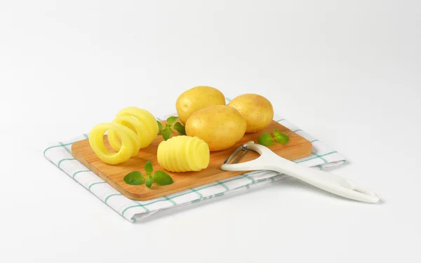 Raw potatoes on cutting board — Stock Photo, Image
