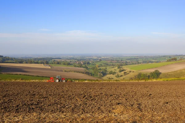 Paisaje otoñal con tractor rojo cultivando y sembrando un campo en octubre —  Fotos de Stock