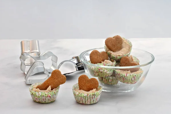 Dog ice cream cookies in a glass bowl with heart and bone shaped dog biscuits on top.  Close up with copy space.