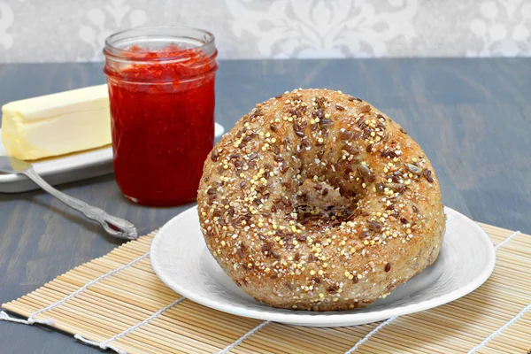 Grão inteiro, bagels multi-semeados com um lado de manteiga e geléia — Fotografia de Stock