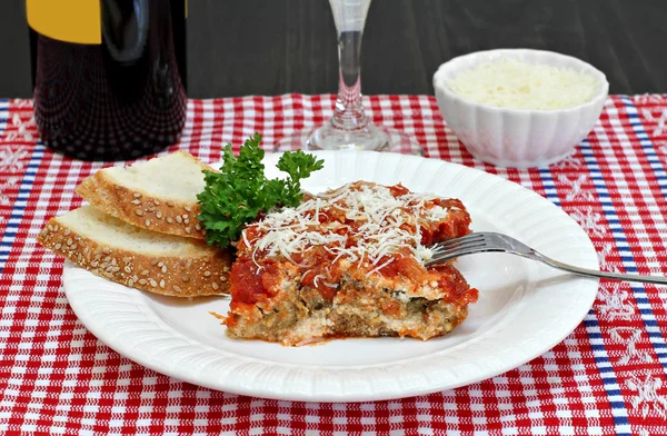 One serving of eggplant parmesan with sides of wine and parmesan — Stock Photo, Image