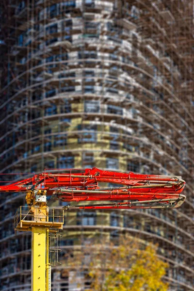 Construction concrete pump (pump truck) with multi-storey building under construction with scaffolding (new residential complex) on the background, Moscow, Russia