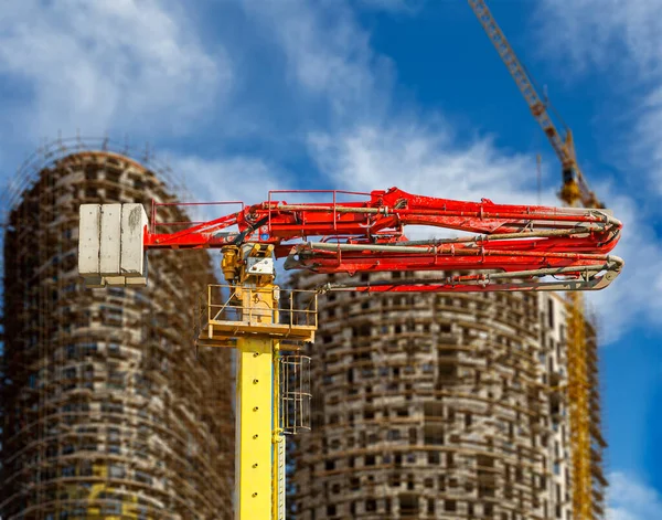 Construction concrete pump (pump truck) with multi-storey building under construction with scaffolding (new residential complex) on the background, Moscow, Russia