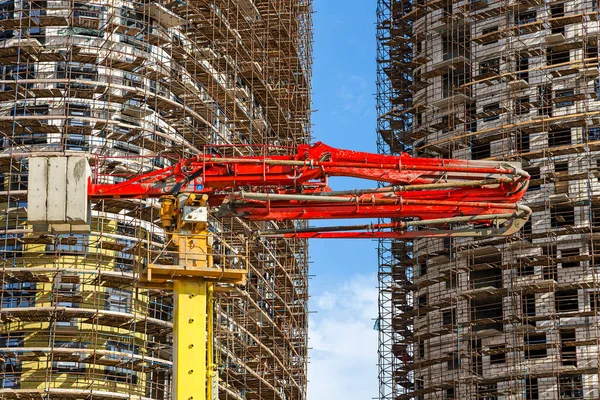 Construction concrete pump (pump truck) with multi-storey building under construction with scaffolding (new residential complex) on the background, Moscow, Russia