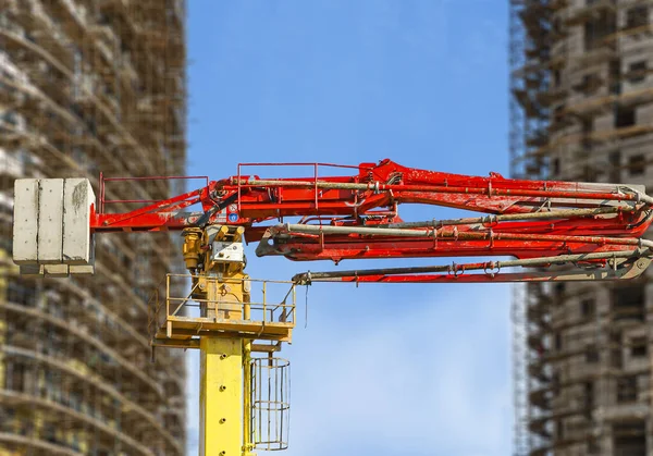 Construction concrete pump (pump truck) with multi-storey building under construction with scaffolding (new residential complex) on the background, Moscow, Russia