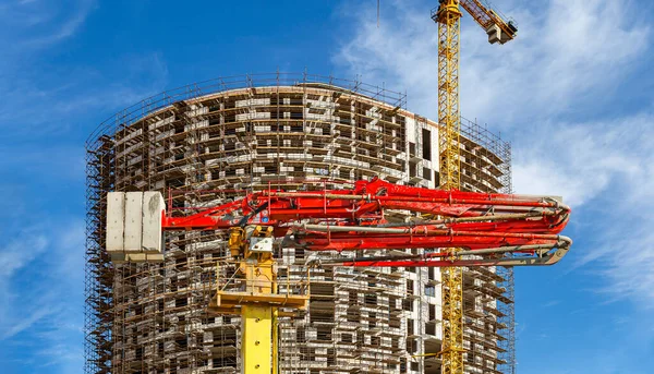 Construction concrete pump (pump truck) with multi-storey building under construction with scaffolding (new residential complex) on the background, Moscow, Russia