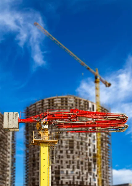 Construction concrete pump (pump truck) with multi-storey building under construction with scaffolding (new residential complex) on the background, Moscow, Russia