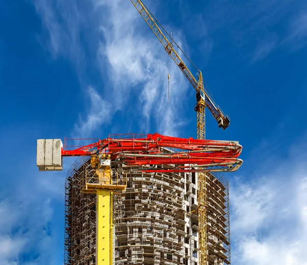 Construction concrete pump (pump truck) with multi-storey building under construction with scaffolding (new residential complex) on the background, Moscow, Russia