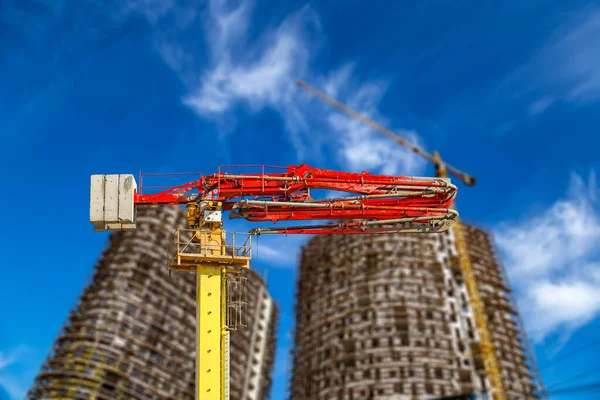 Construction concrete pump (pump truck) with multi-storey building under construction with scaffolding (new residential complex) on the background, Moscow, Russia