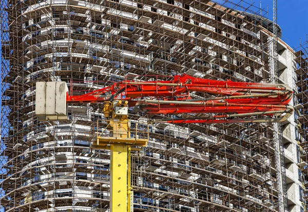 Construction concrete pump (pump truck) with multi-storey building under construction with scaffolding (new residential complex) on the background, Moscow, Russia