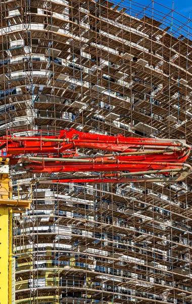 Construction concrete pump (pump truck) with multi-storey building under construction with scaffolding (new residential complex) on the background, Moscow, Russia