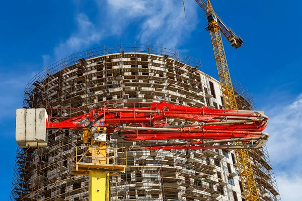 Construction concrete pump (pump truck) with multi-storey building under construction with scaffolding (new residential complex) on the background, Moscow, Russia