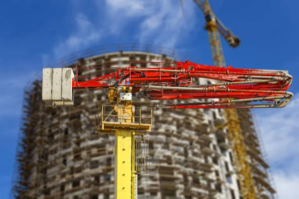 Construction concrete pump (pump truck) with multi-storey building under construction with scaffolding (new residential complex) on the background, Moscow, Russia