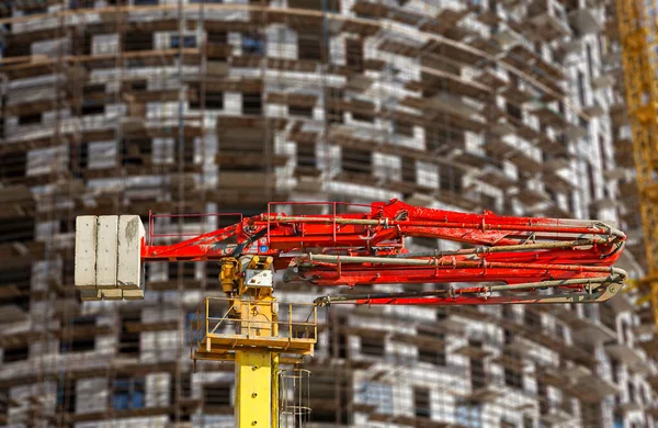 Construction concrete pump (pump truck) with multi-storey building under construction with scaffolding (new residential complex) on the background, Moscow, Russia