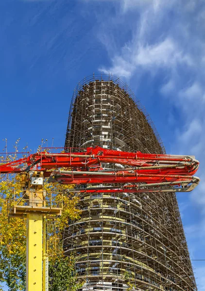 Construction concrete pump (pump truck) with multi-storey building under construction with scaffolding (new residential complex) on the background, Moscow, Russia