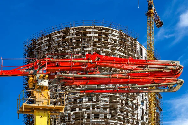 Construction concrete pump (pump truck) with multi-storey building under construction with scaffolding (new residential complex) on the background, Moscow, Russia