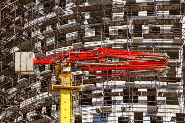 Arka planda inşaat halindeki çok katlı bina iskelesi (yeni iskan kompleksi) olan beton pompa (pompa kamyonu), Moskova ve Rusya