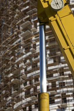 İnşaat makinesinin bir parçası (kazıcı veya vinç) arka planda iskele (yeni iskan kompleksi) bulunan çok katlı bina, Moskova, Rusya