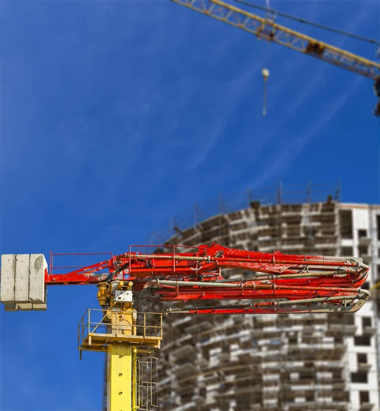 Construction concrete pump (pump truck) with multi-storey building under construction with scaffolding (new residential complex) on the background, Moscow, Russia