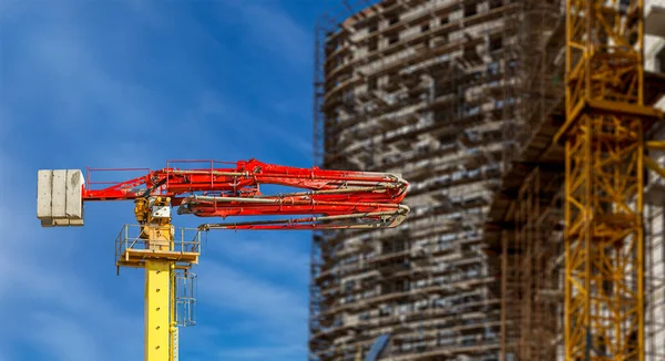 Construction concrete pump (pump truck) with multi-storey building under construction with scaffolding (new residential complex) on the background, Moscow, Russia