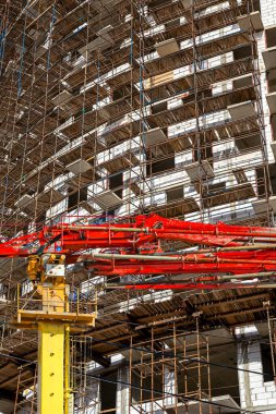 Arka planda inşaat halindeki çok katlı bina iskelesi (yeni iskan kompleksi) olan beton pompa (pompa kamyonu), Moskova ve Rusya