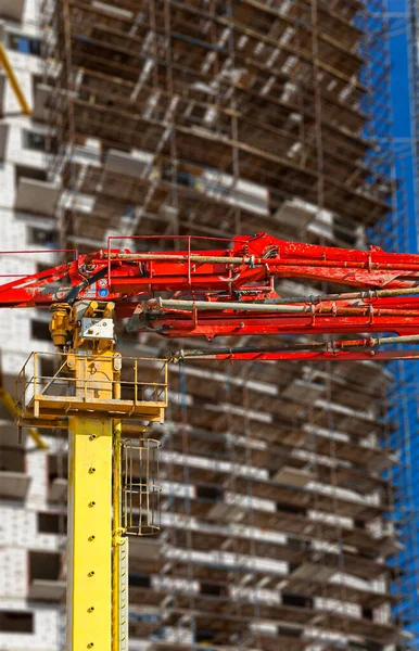 Construction concrete pump (pump truck) with multi-storey building under construction with scaffolding (new residential complex) on the background, Moscow, Russia