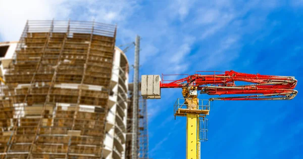 Construction concrete pump (pump truck) with multi-storey building under construction with scaffolding (new residential complex) on the background, Moscow, Russia