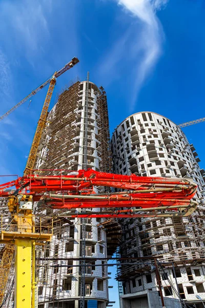 Construction concrete pump (pump truck) with multi-storey building under construction with scaffolding (new residential complex) on the background, Moscow, Russia