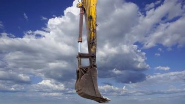 Hareket eden bulutlara karşı bir inşaat makinesinin parçası (kazıcı veya vinç) 