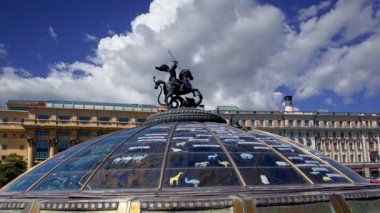 Manege Meydanı (Moskova 'nın kutsal koruyucusu Aziz George' un heykeli tarafından taçlandırılan cam kubbe) hareket eden bulutlar, Rusça yazıtlar: dünyanın ünlü şehirlerinin isimleri, Moskova, Rusya 