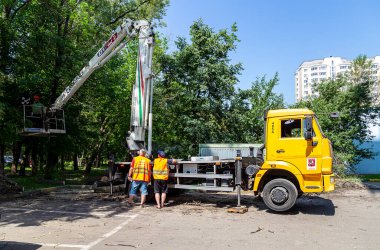 MOSCOW, RUSSIA - 23 Haziran 2021: bir yerleşim yerinin avlusunda hidrolik kaldırma tesisi olan bir araba. Kuru dallar budamak, hasarlı ağaçları kesmek, kronlama. Şehir hizmetlerinin çalışması.