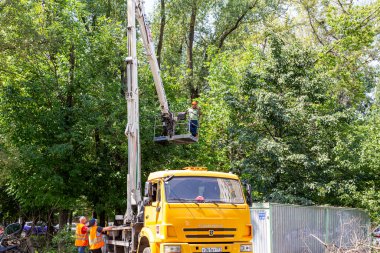 MOSCOW, RUSSIA - 23 Haziran 2021: bir yerleşim yerinin avlusunda hidrolik kaldırma tesisi olan bir araba. Kuru dallar budamak, hasarlı ağaçları kesmek, kronlama. Şehir hizmetlerinin çalışması.