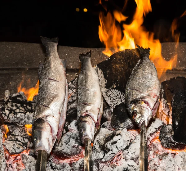 Cooking fish grilled over hot coals bonfire — Stock Photo, Image