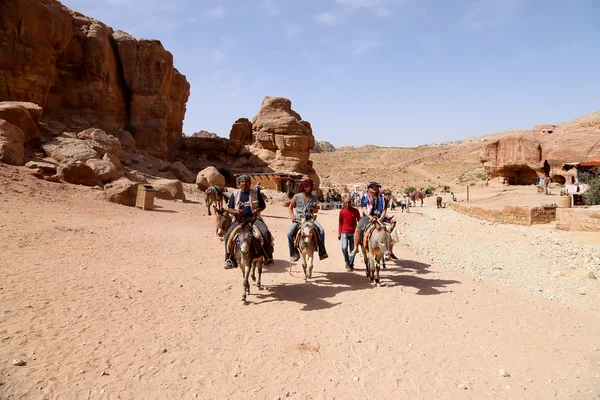 Touristen mit Beduinen besuchen die antiken Ruinen von Petra auf Eseln, Jordanien — Stockfoto