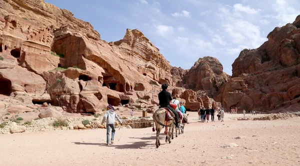 Touristes avec des Bédouins visitant les ruines antiques de Petra sur des ânes, Jordanie — Photo