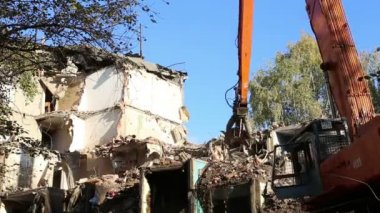 Hidrolik kırıcı ekskavatör makine yıkım eski ev üzerinde çalışıyor. Moskova, Rusya