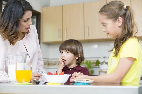 Mooie moeder en haar kinderen ontbijten — Stockfoto